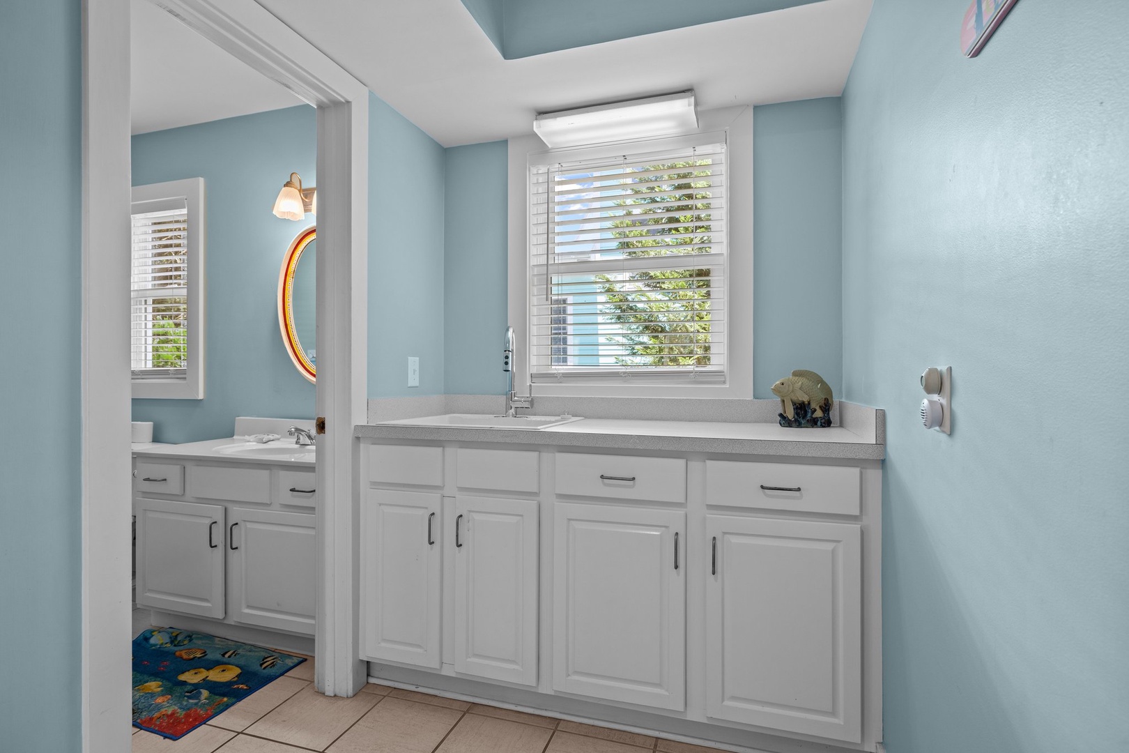 Refresh in your bright, coastal-themed bathroom featuring sleek white cabinetry and calming blue walls that create a serene spa-like atmosphere.