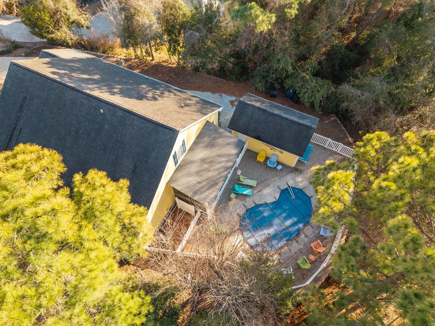 Aerial view of the property showcasing the main building, swimming pool, and lush natural surroundings nestled among mature trees.