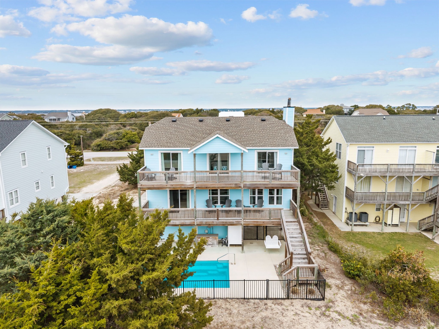 Aerial view of beachfront vacation homes nestled among coastal vegetation, with swimming pools and easy beach access in this scenic waterfront community.
