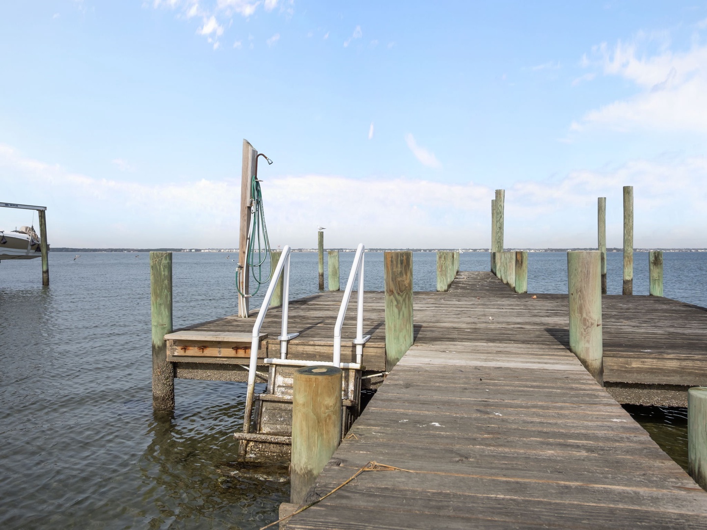 Private waterfront dock extends into calm bay waters, offering direct access for boating adventures and peaceful moments by the water.