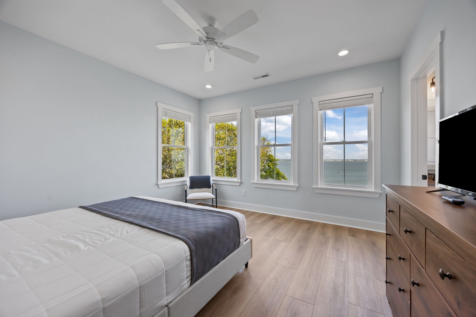 Your serene bedroom sanctuary with stunning water views through bay windows. Ceiling fan keeps you comfortable while watching boats drift by.