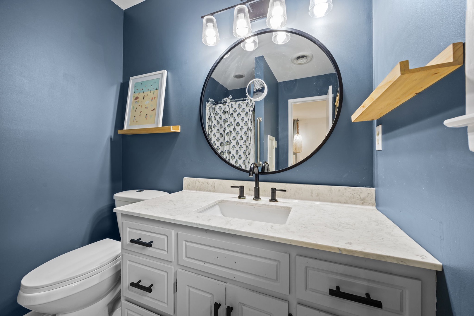 Your stylish powder room features elegant blue walls, marble countertops, and thoughtful touches that make freshening up a luxurious experience.