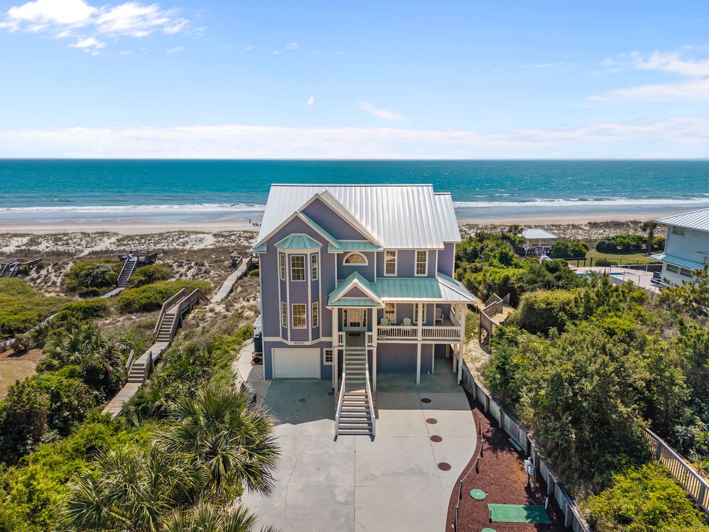 Stunning beachfront home with direct beach access, surrounded by lush coastal vegetation and pristine sandy shores.