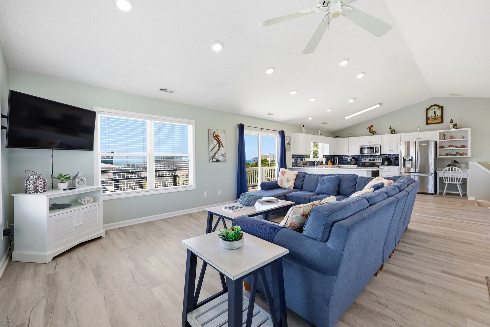 Unwind on plush blue sofas in this bright, open-concept living space with coastal views. The spacious layout flows into a fully-equipped kitchen, perfect for gathering after a day at the beach.
