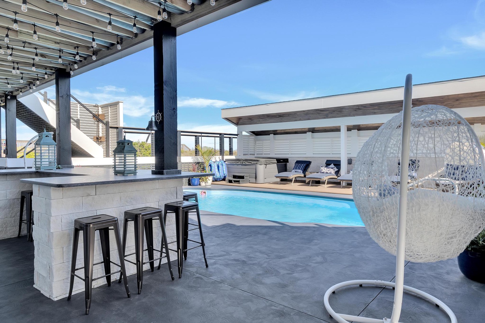 Sip morning coffee at the bar or lounge in the hanging chair overlooking your private pool—a perfect blend of relaxation and modern style under sunny skies.