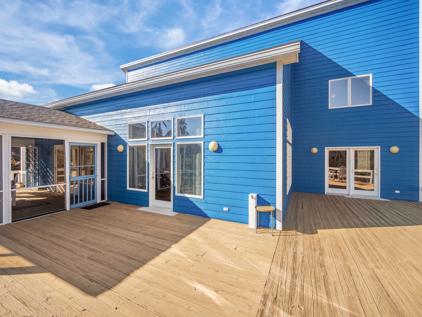 Modern blue beach house with expansive deck offering oceanfront charm and sunny outdoor living spaces.