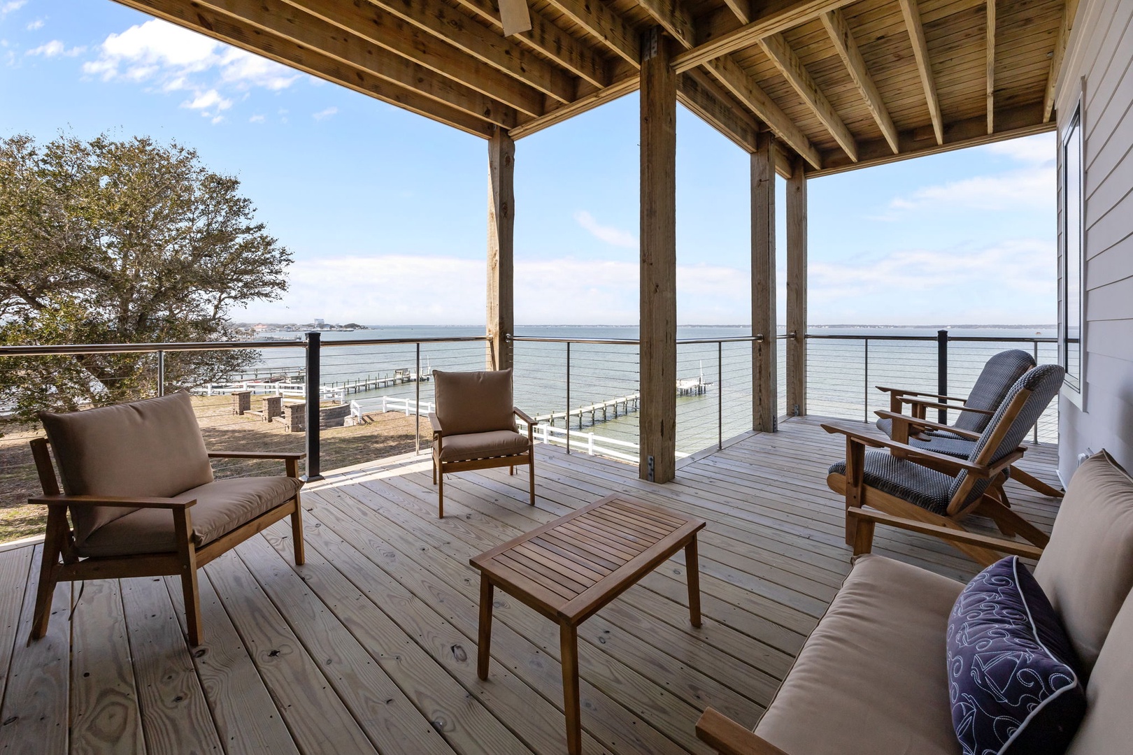 Waterfront deck with comfortable seating overlooking peaceful waters and scenic docks - your perfect spot to unwind.
