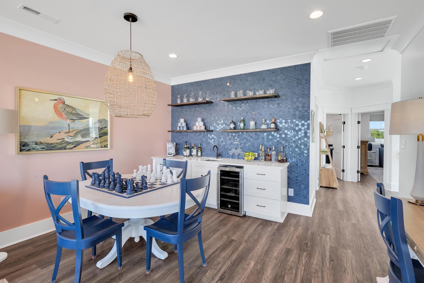 Your stylish game room features a chessboard-ready table, coastal-chic blue accents, and a stunning wet bar with mosaic tile and wine fridge—perfect for relaxing evenings in.