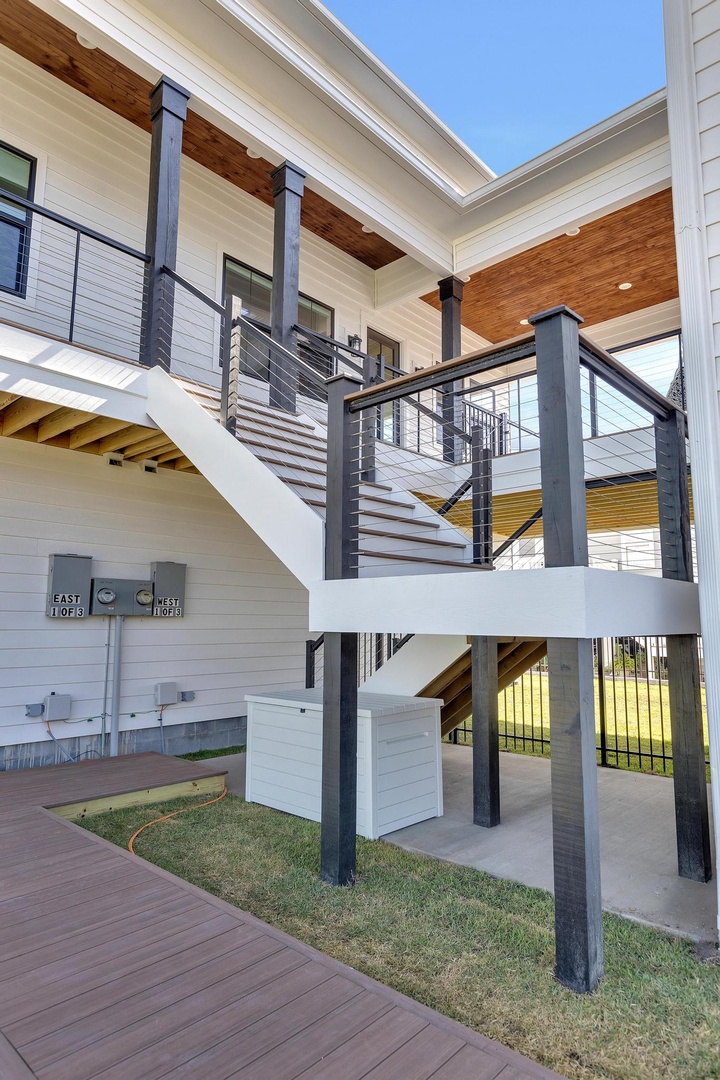 Modern elevated property featuring a striking staircase, wood-paneled ceilings, and clean architectural lines under clear blue skies—a stylish coastal retreat with contemporary design.