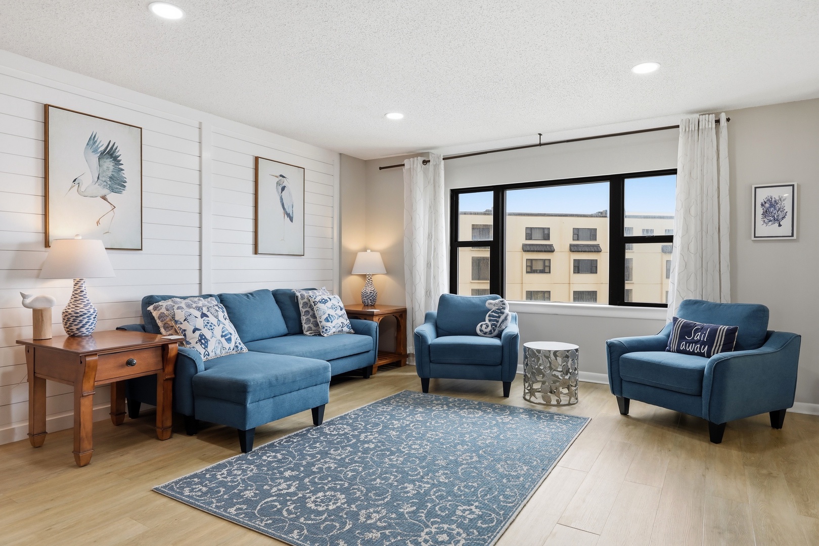 Unwind in your serene living space, where coastal blues and natural textures create the perfect backdrop for your relaxing getaway. Light floods through large windows, inviting you to settle in.