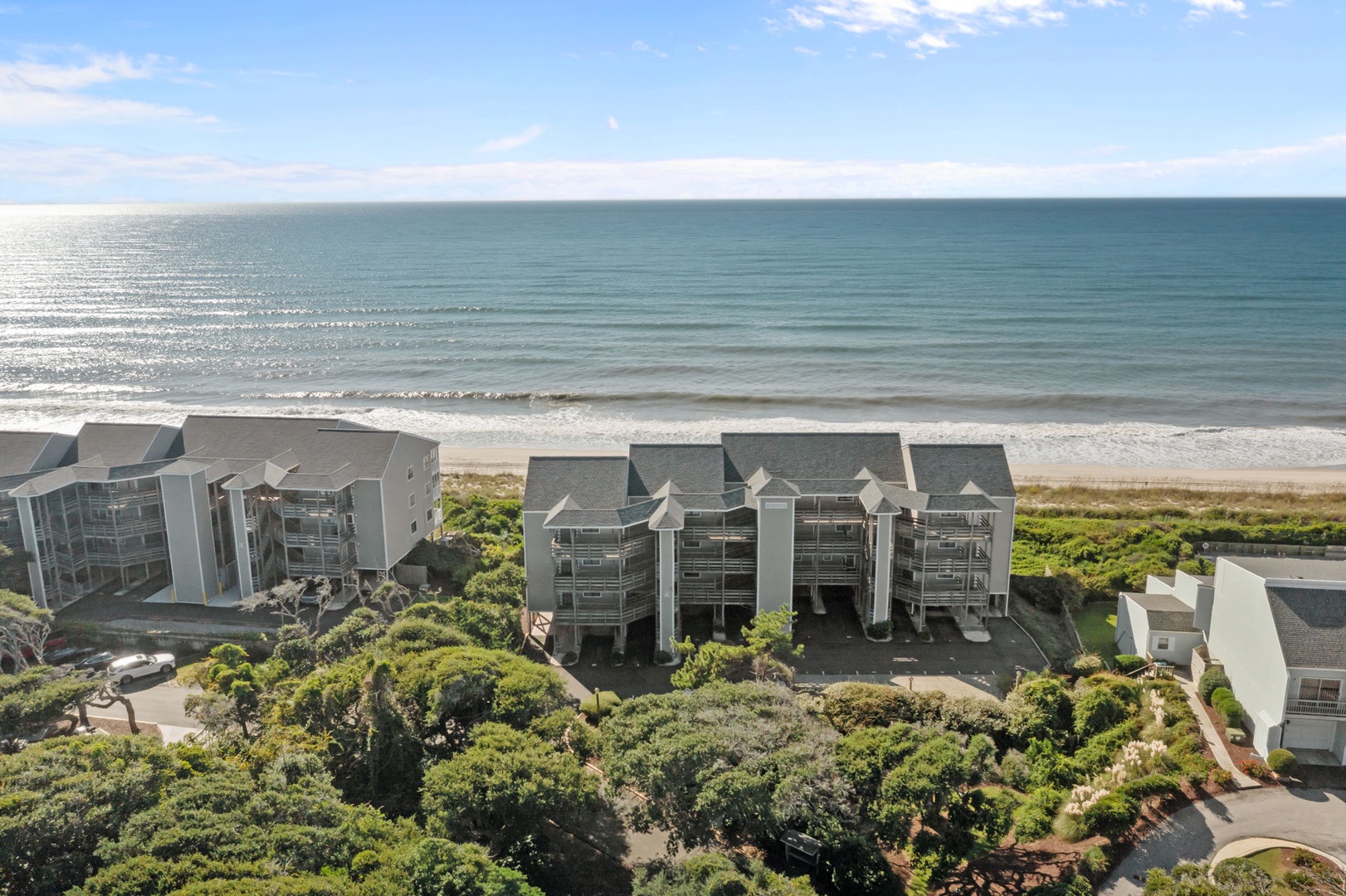 Oceanfront resort buildings nestled among lush coastal vegetation with direct beach access and pristine shoreline views.