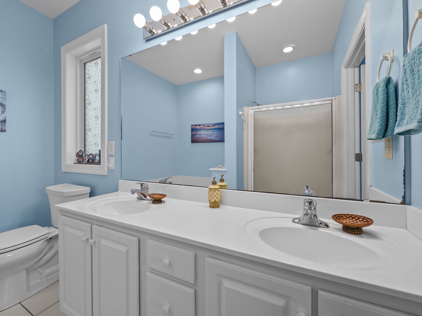 Step into your serene bathroom oasis with calming blue walls, dual vanity, and warm lighting that makes your morning routine feel luxurious.