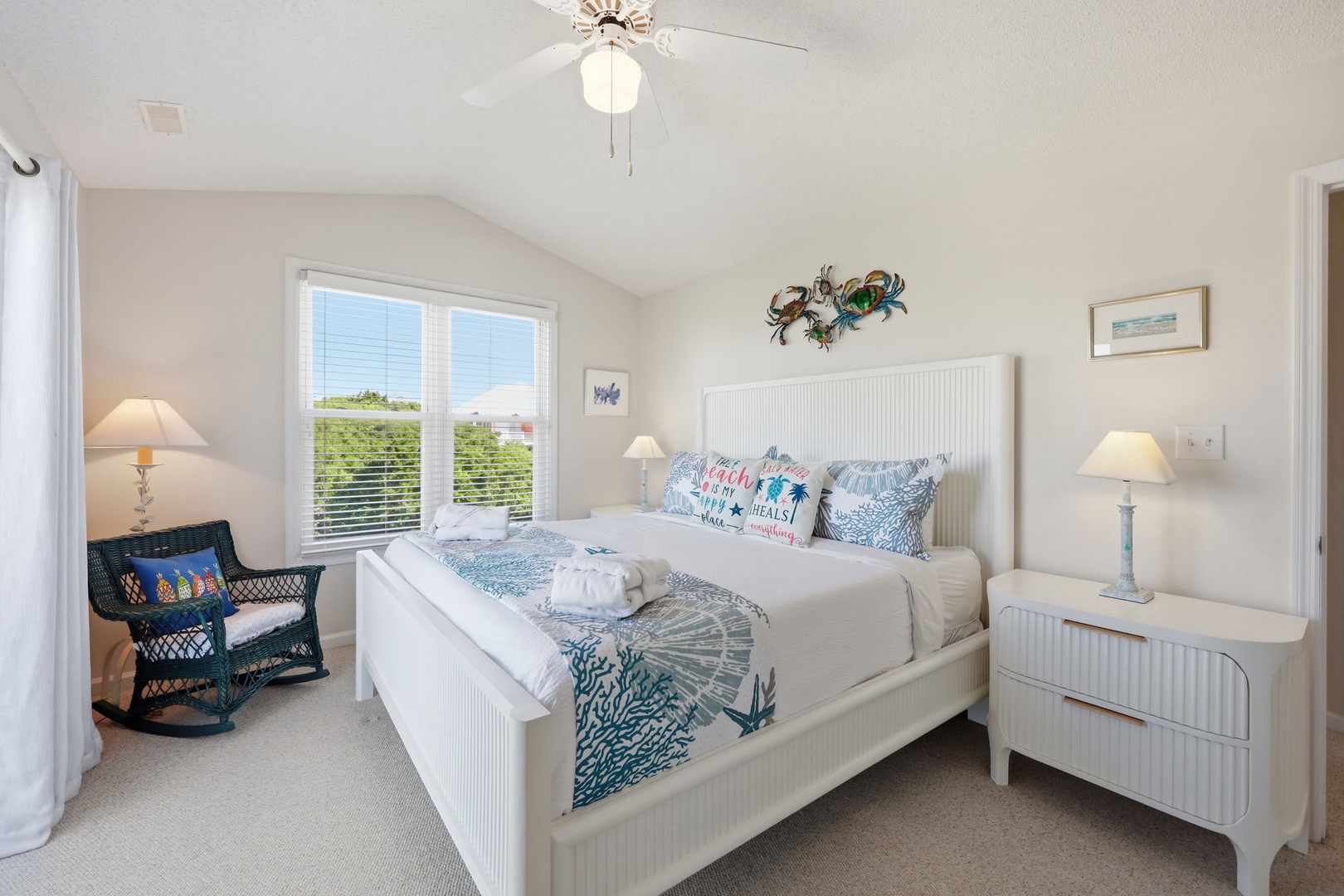 Sink into crisp white linens and ocean-inspired accents in your light-filled bedroom, where coastal charm meets comfort and every morning starts with natural light streaming through your windows.