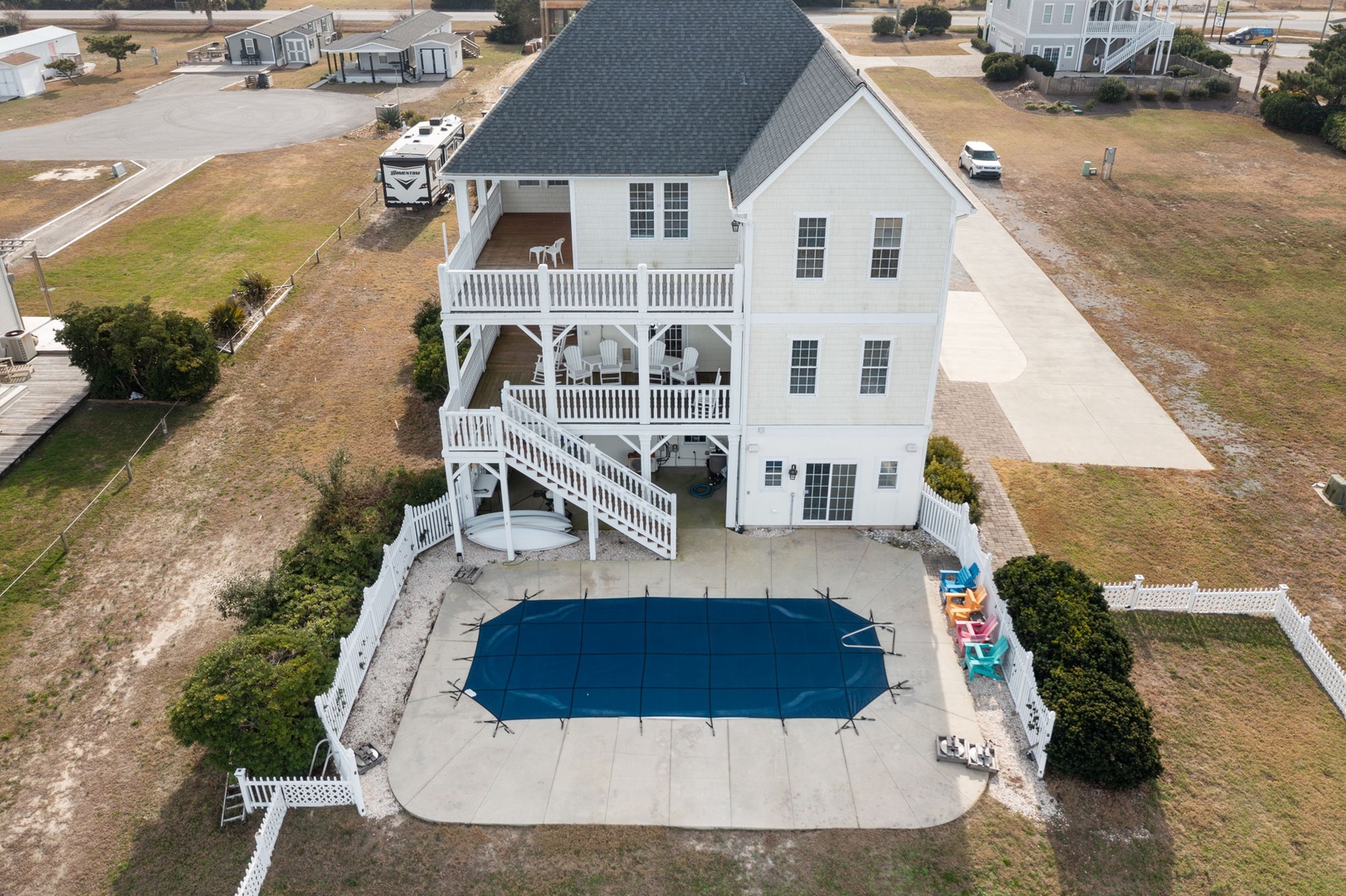 Stunning aerial view showcases this beach house retreat with private pool, multi-level decks, and spacious grounds in a peaceful residential setting.