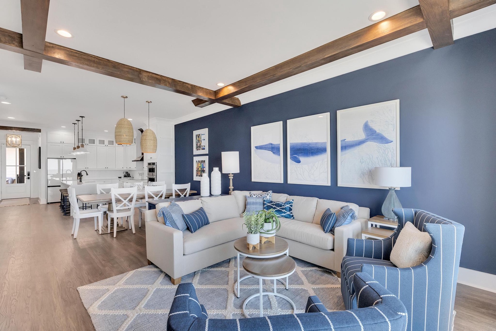 Picture yourself relaxing in this bright coastal retreat, with exposed beams overhead and nautical artwork setting the tone. The open living space flows seamlessly into the dining area and modern kitchen—perfect for your getaway.