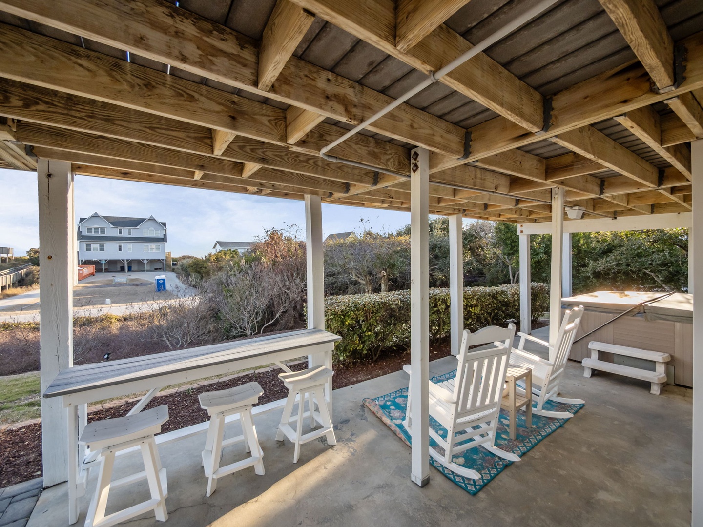 Relax in your covered outdoor living space with comfortable seating and peaceful neighborhood views beyond the landscaped garden.