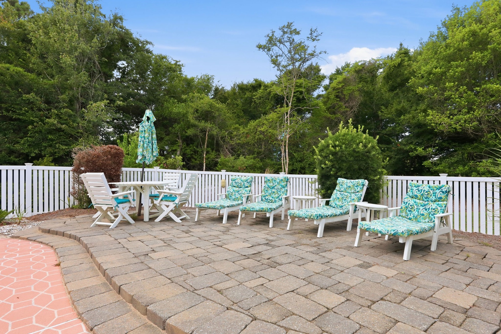 Settle into these cushioned lounge chairs on the spacious patio, where you can soak up the sun surrounded by lush greenery and enjoy peaceful outdoor moments.