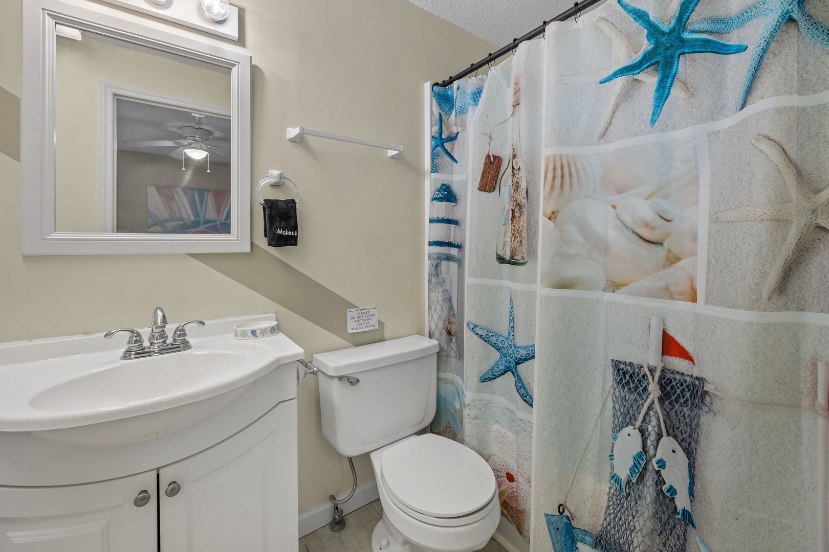 Your coastal-themed bathroom features a charming starfish and seashell shower curtain that brings the beach indoors.