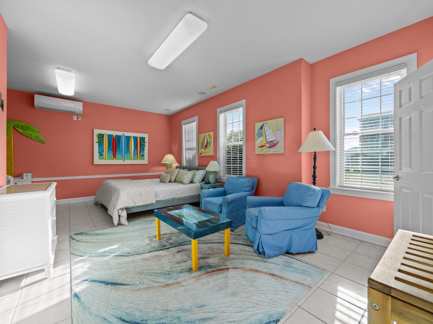 Unwind in your vibrant tropical suite where coral walls and ocean blues create a cheerful retreat with comfortable seating and peaceful atmosphere.