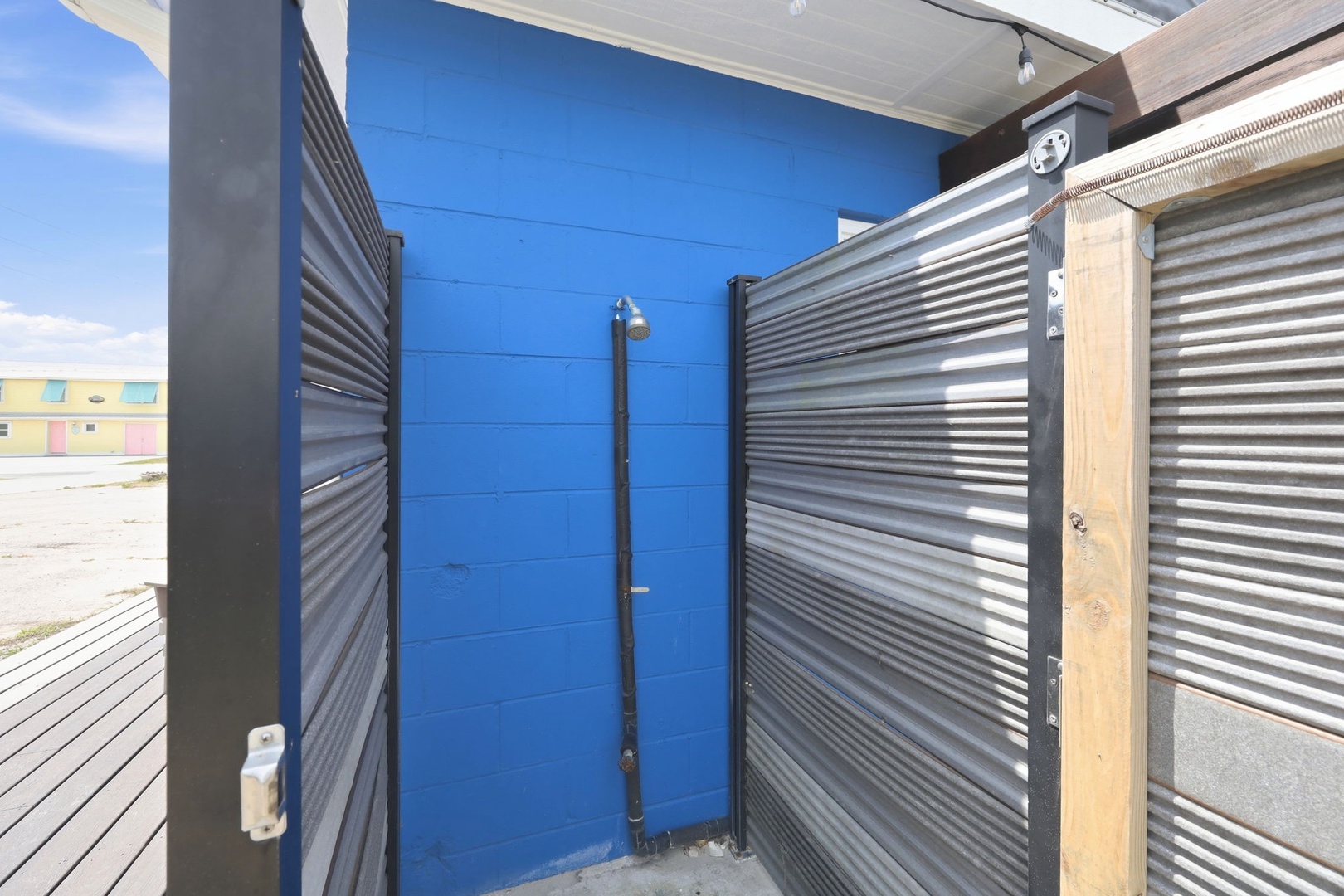Outdoor shower with corrugated metal privacy walls, ideal for rinsing off after beach days or outdoor adventures.