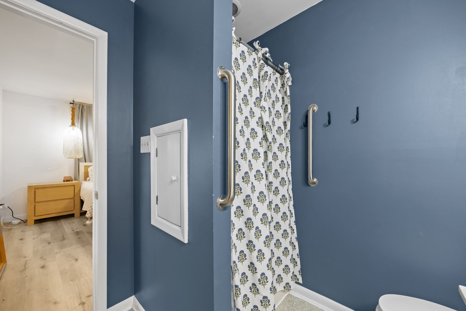 Step into your accessible bathroom with thoughtful grab bars and charming floral shower curtain for comfort and safety.