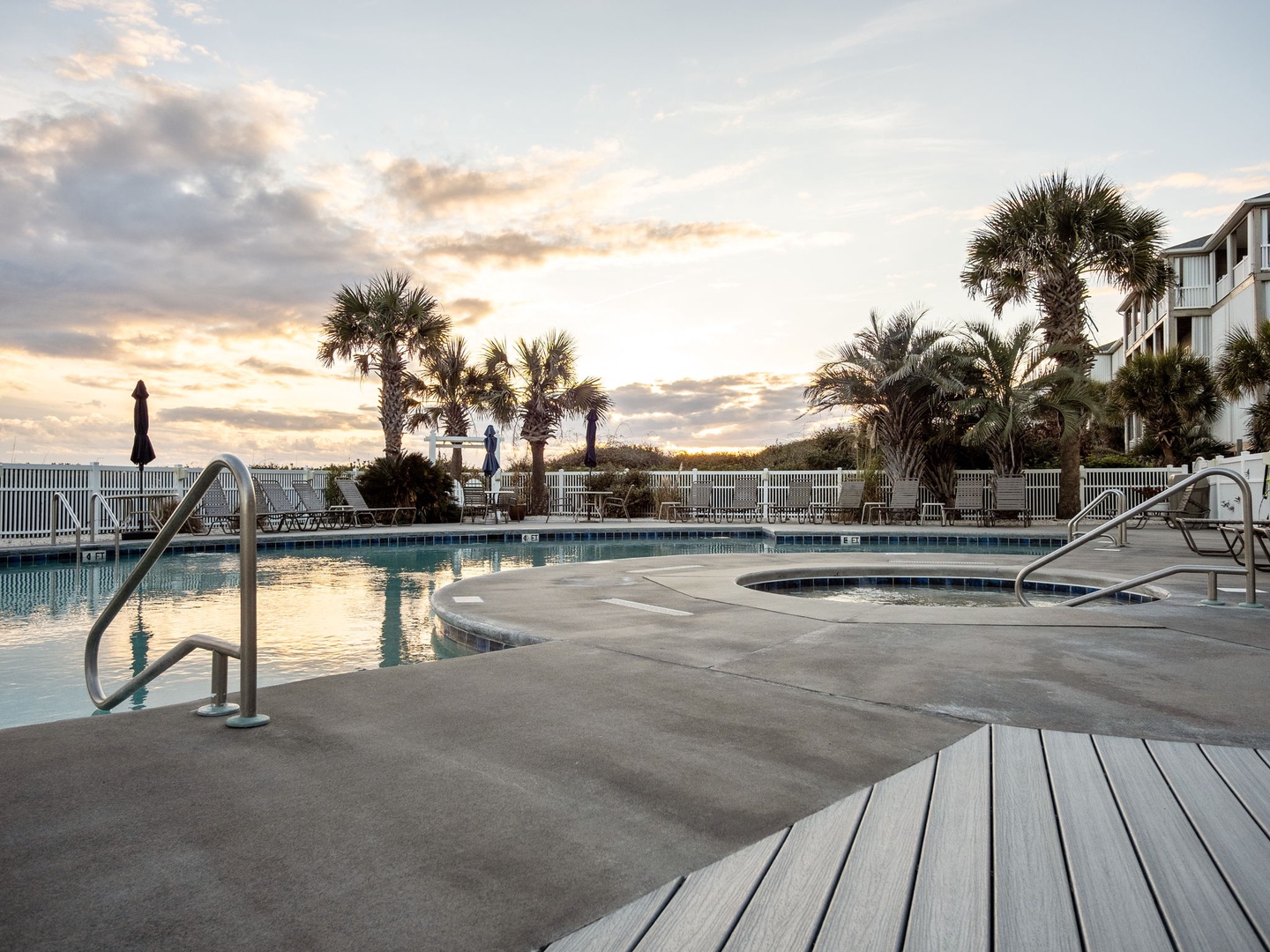 Coastal pool deck with palm trees and property buildings capturing the golden hour atmosphere of this beachfront location.