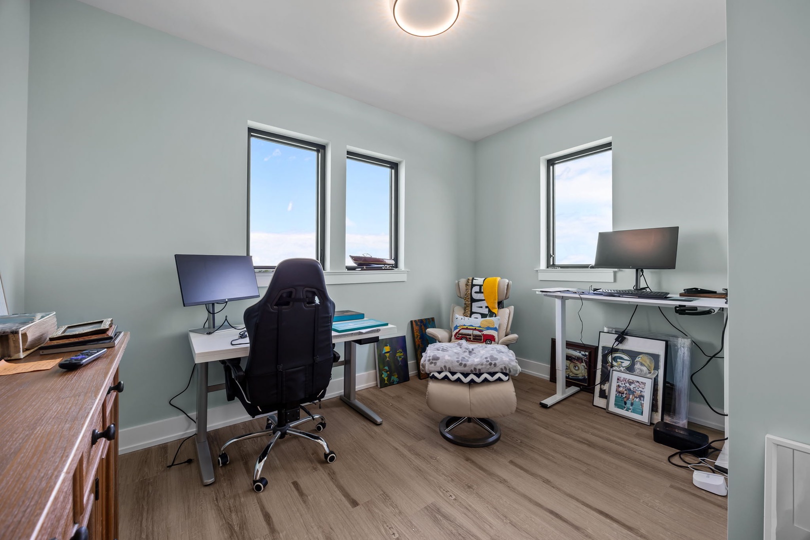 Stay productive in your dedicated workspace with dual monitor setup, ergonomic seating, and natural light streaming through multiple windows.