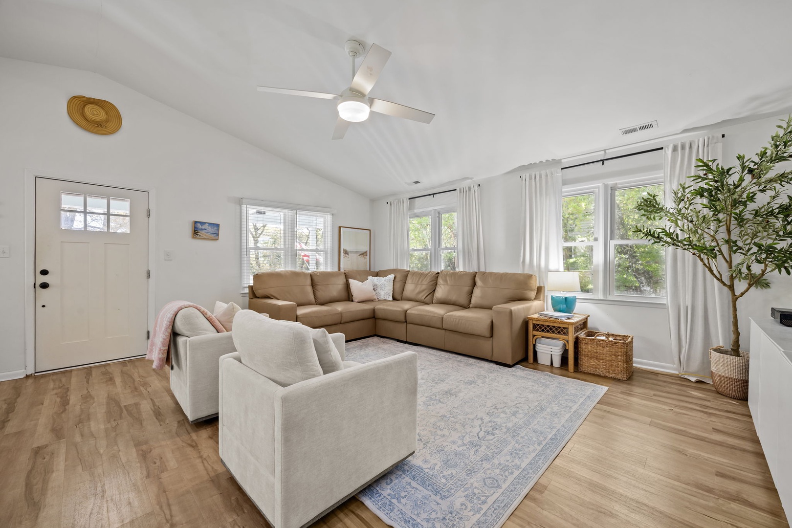 Sink into plush sectional seating in your bright living space, where natural light streams through large windows and a ceiling fan keeps you comfortable.