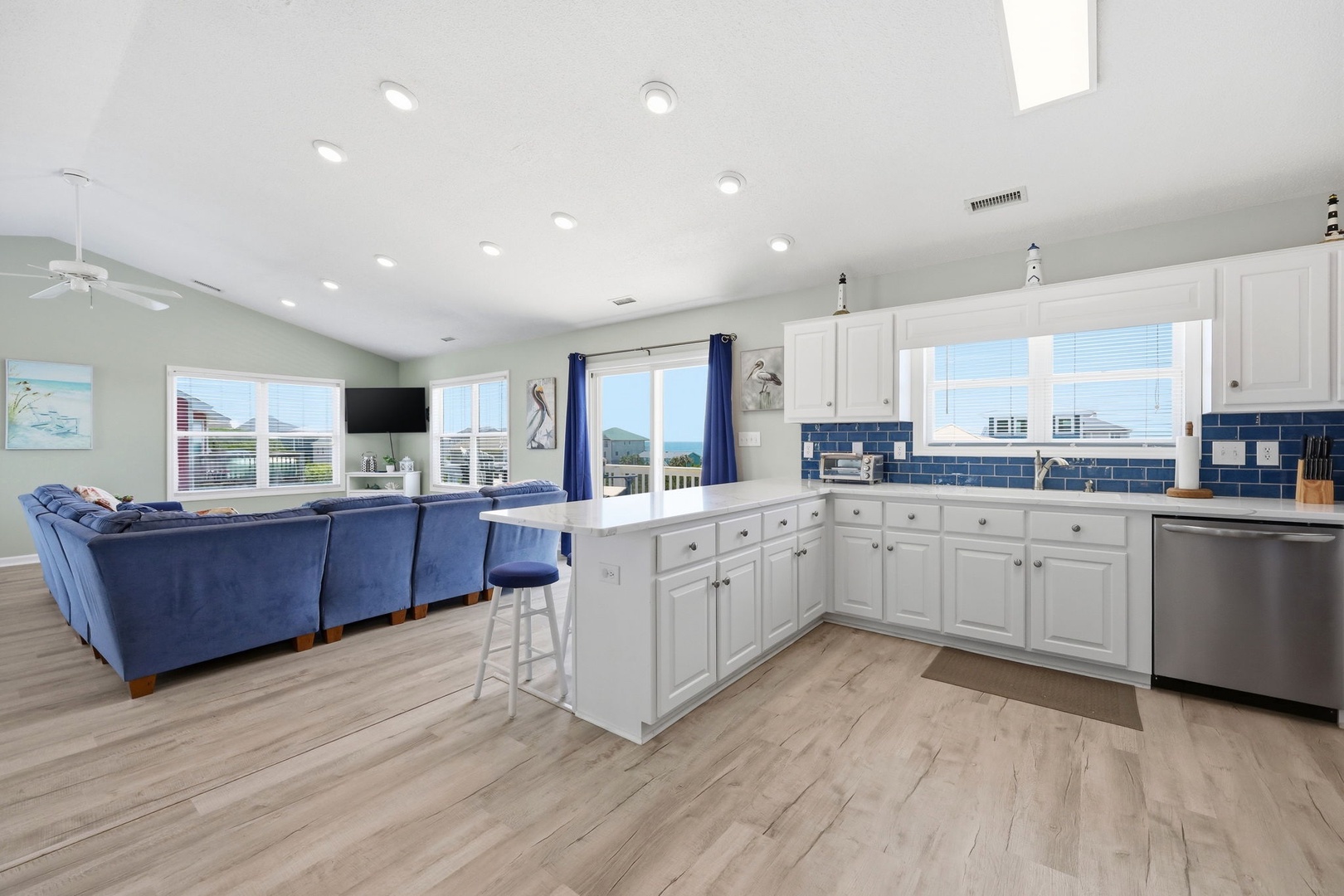 Sunlight streams through expansive windows as you relax in your open-concept living area. Cook, dine, and unwind in this bright, modern space with mountain views and coastal-inspired design.