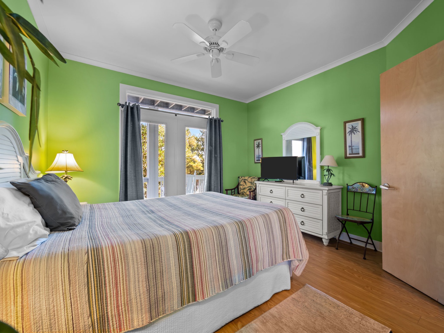 Your tropical bedroom retreat features bright green walls, ceiling fan, TV, and French doors opening to your private outdoor space.