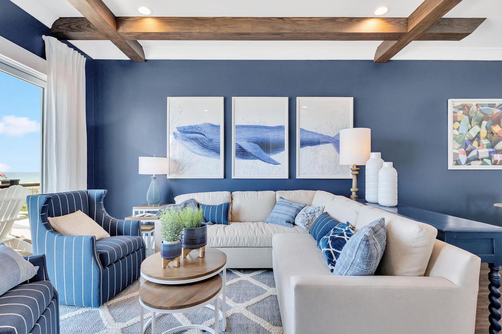 Sink into plush seating beneath vaulted wood beams while ocean breezes drift through your windows. Coastal artwork and soft blue tones create your perfect seaside retreat.