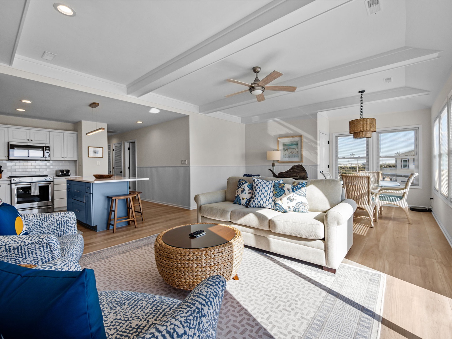 Relax in your bright, coastal-inspired living space with comfortable seating, exposed beams, and an open kitchen perfect for preparing meals together.