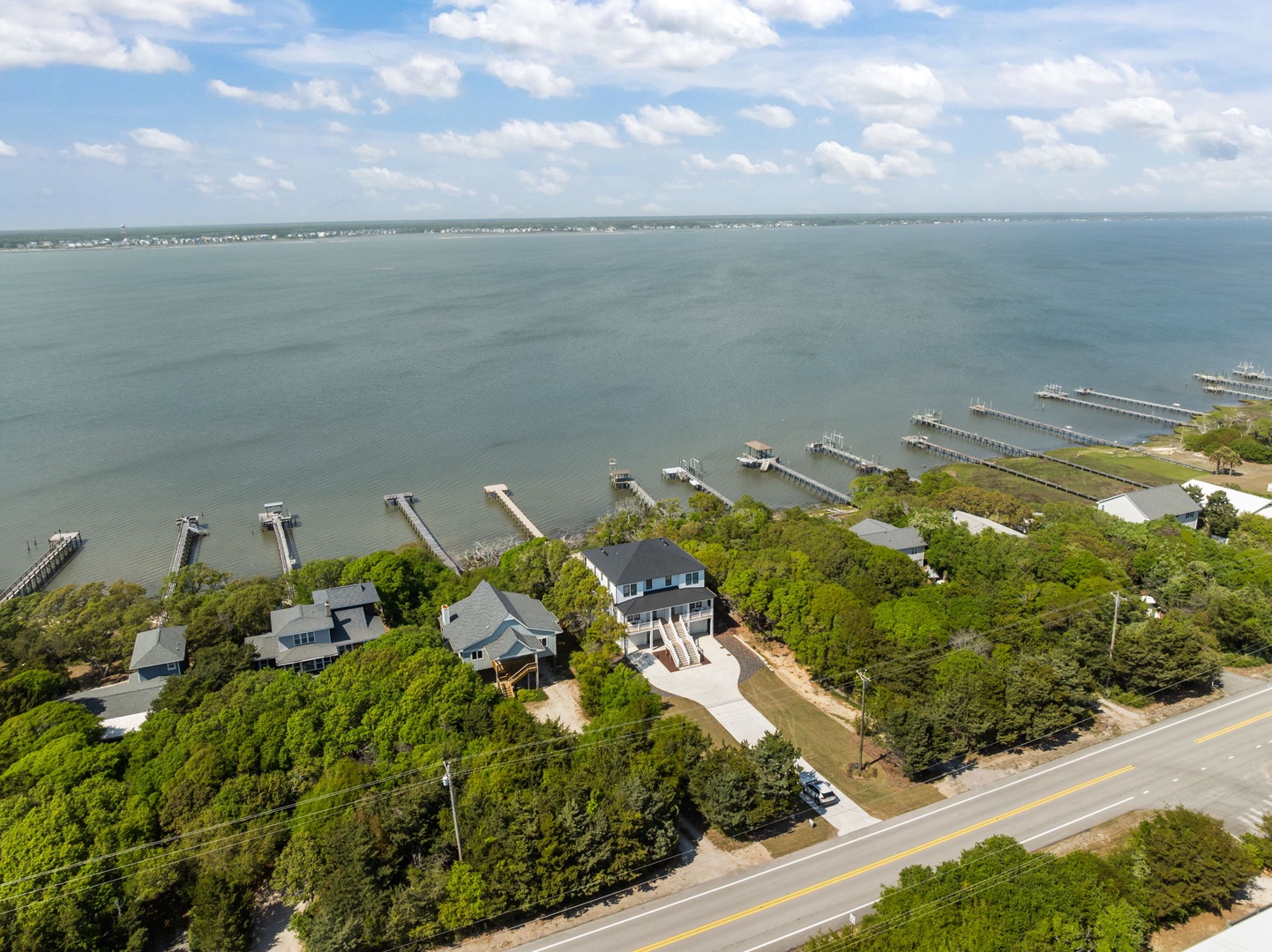 Aerial view of waterfront properties nestled among mature trees with private boat docks extending into the expansive bay waters.