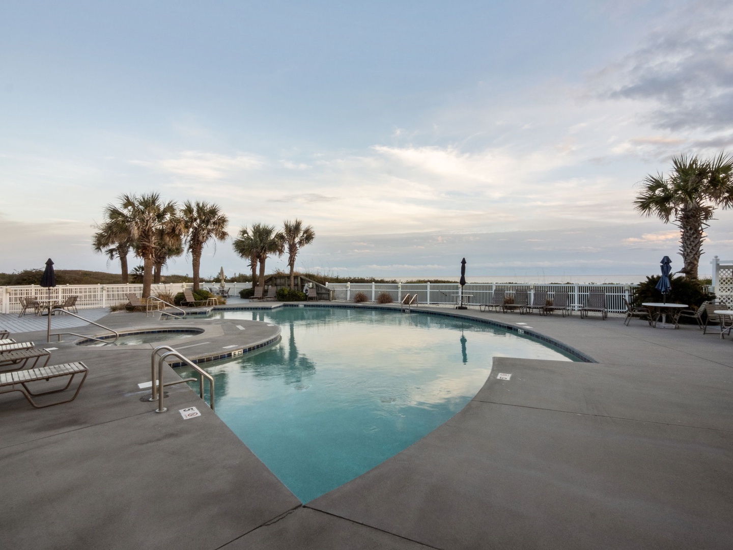 Beachfront pool area featuring crystal-clear waters, tropical palm trees, and coastal views perfect for relaxation.