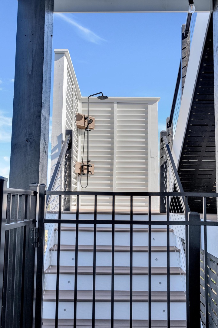 An outdoor shower with dual showerheads provides a refreshing rinse under the open sky, perfect for cooling off after a beach day or poolside lounging.