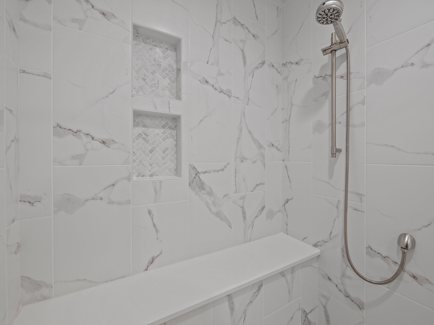 Step into your luxurious marble shower sanctuary, where elegant built-in niches hold your essentials and the rainfall head promises rejuvenating moments.