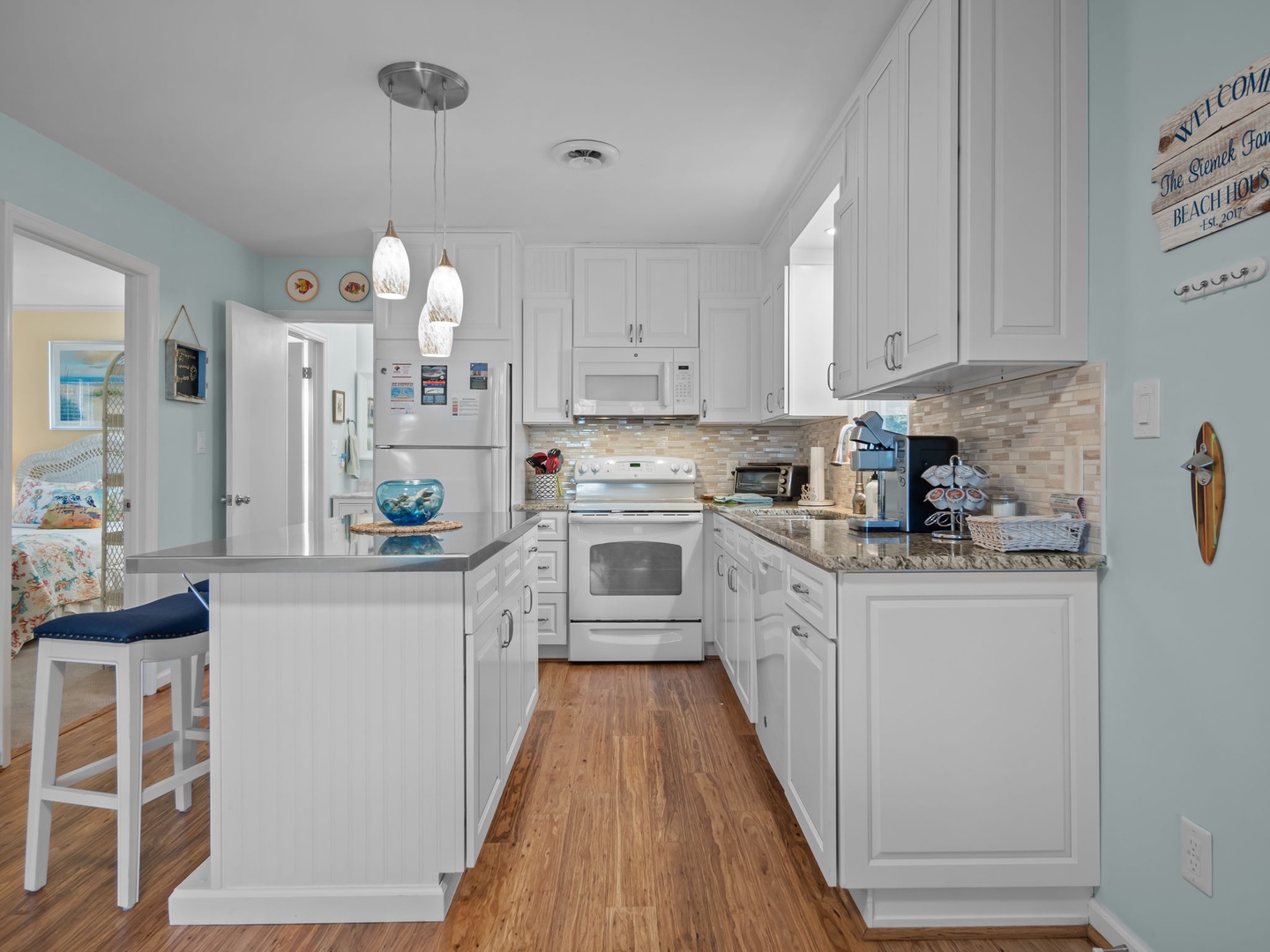 Your coastal-inspired kitchen invites you to prepare meals surrounded by soothing sea glass walls and pristine white cabinetry, complete with modern appliances.