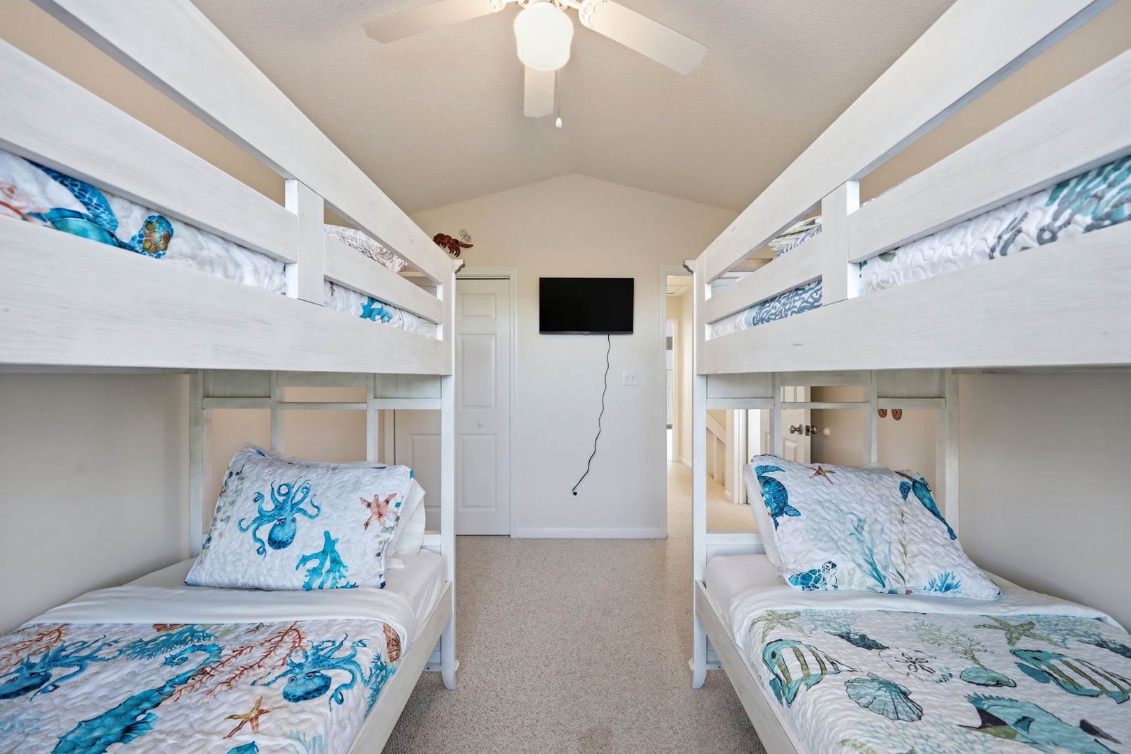 Four cozy bunk beds with ocean-themed bedding create the perfect sleep space for kids or groups, with a wall-mounted TV for movie nights together.