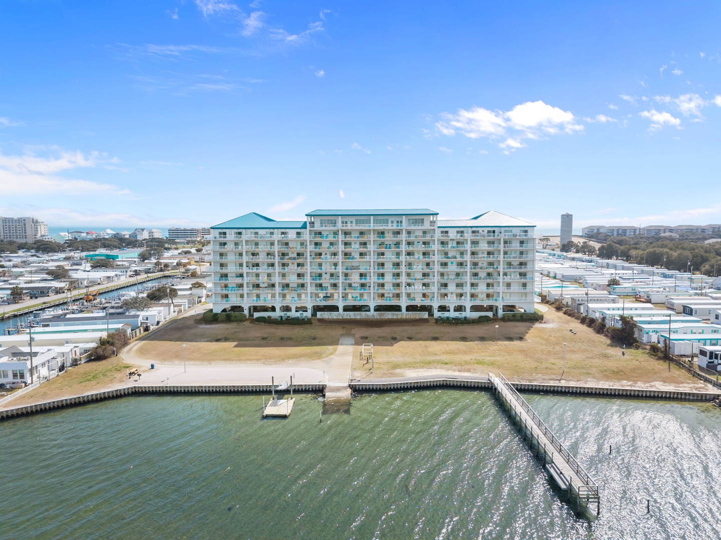 Waterfront resort complex featuring multiple buildings with distinctive turquoise roofing, positioned along a protected marina with private docks and boat access.