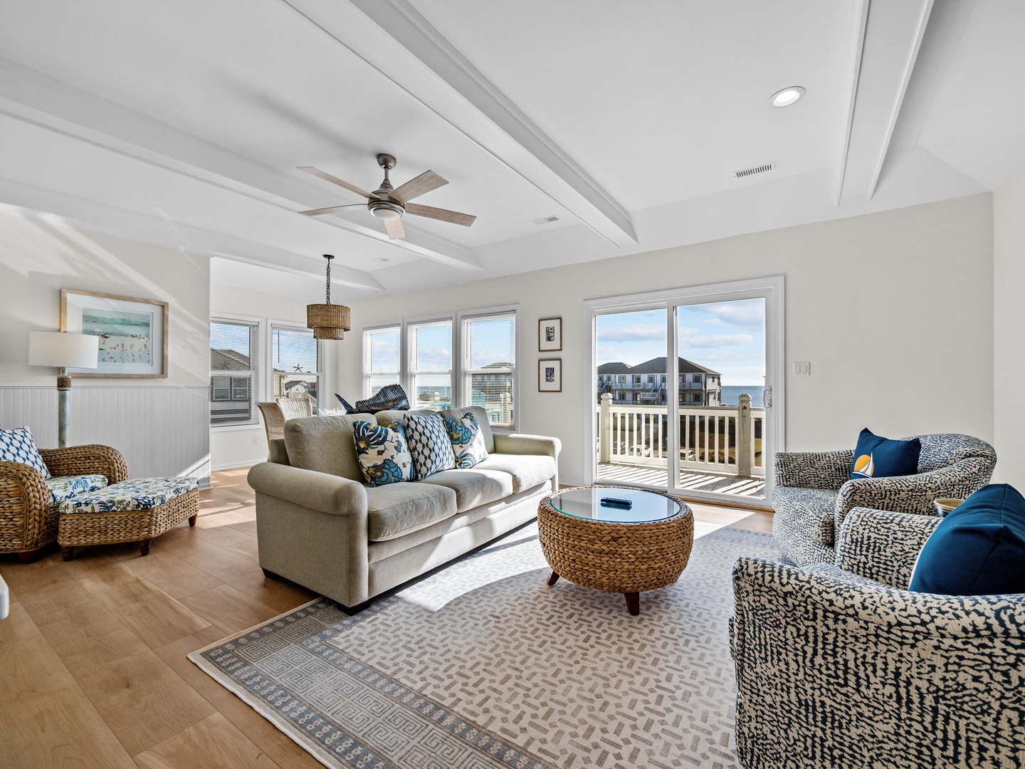 Relax in your bright coastal living room with panoramic windows, comfortable seating, and charming coffered ceilings.