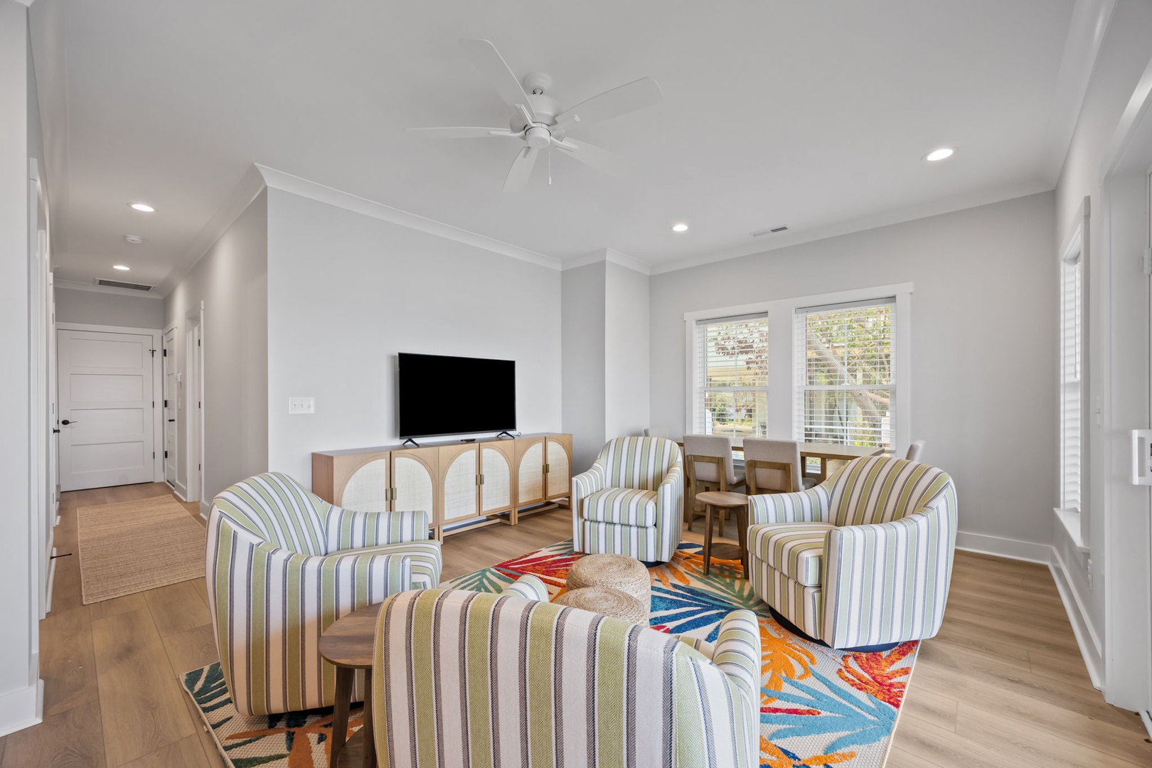 Relax in your stylish living space with comfortable striped seating and bright natural light streaming through large windows.