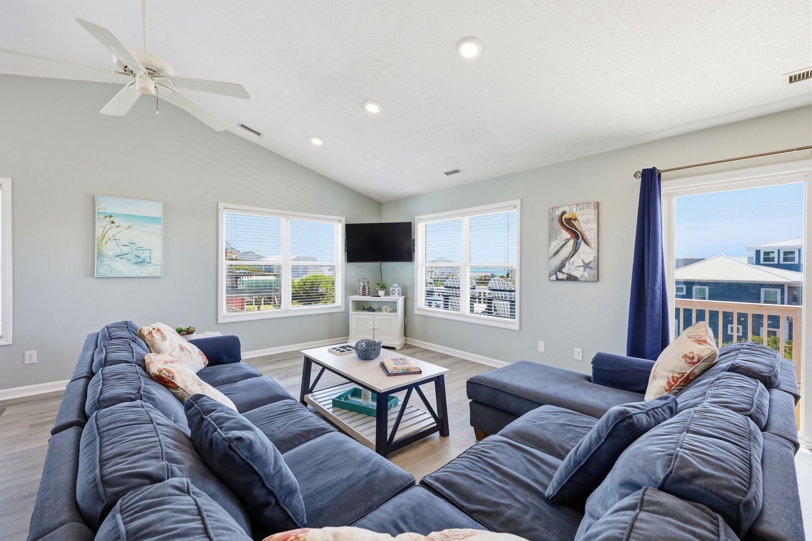 Unwind in your bright living space with plush seating, coastal art, and large windows framing stunning water and neighborhood views. Perfect for gathering after a beach day.
