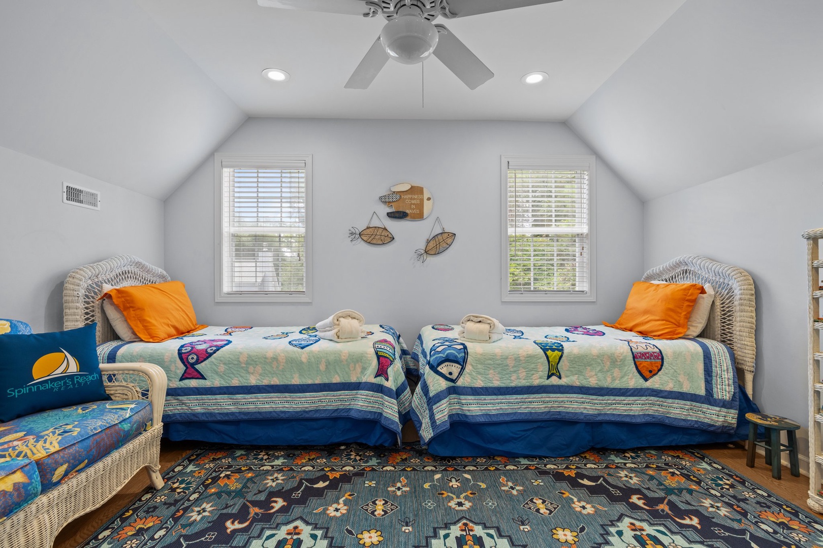 Your kids will love this cheerful bedroom with twin beds, colorful fish-themed bedding, and nautical wall art.