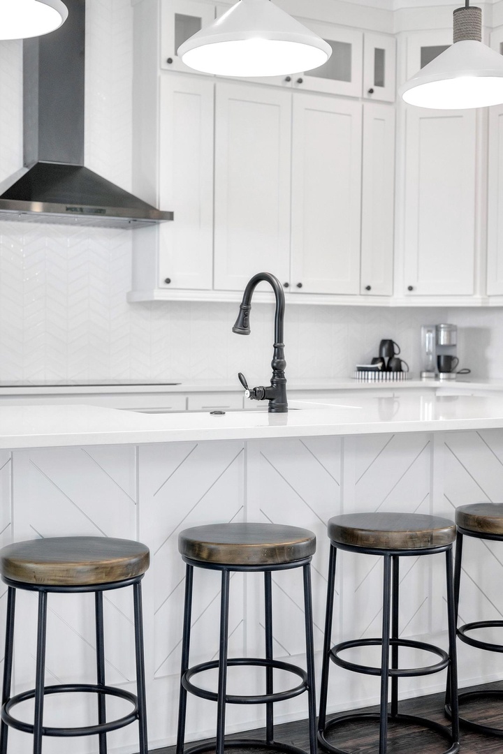 Gather at the sleek island under modern pendant lights. White cabinetry and clean countertops give you a bright, open space to whip up meals or sip morning coffee.