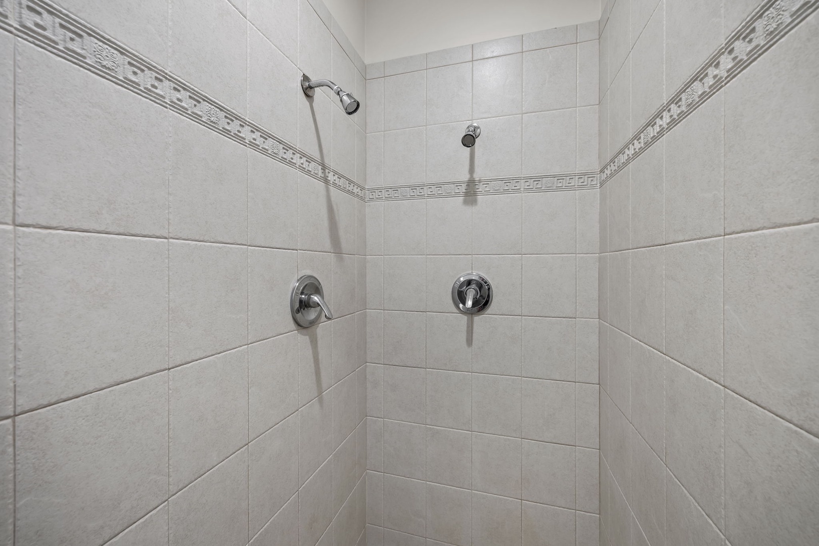 Step into your private dual-head shower sanctuary with elegant tiled walls and chrome fixtures for a refreshing start to each day.