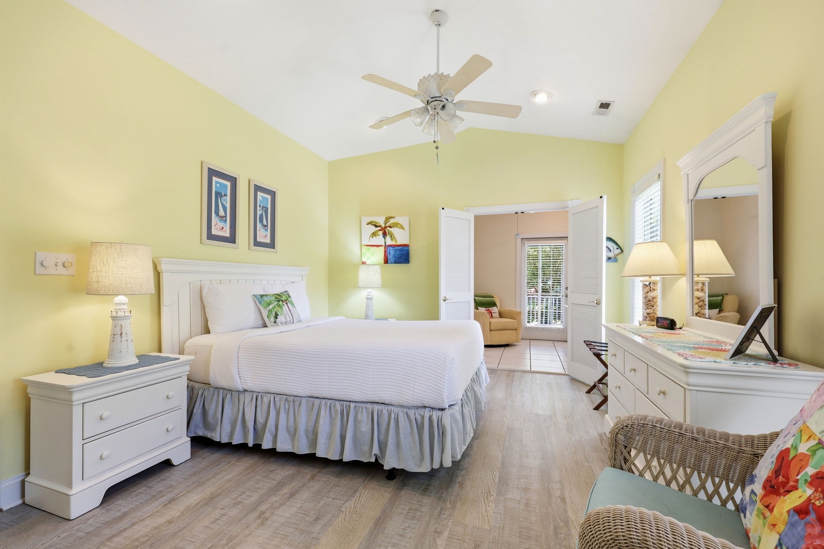 Relax in this sunny, coastal-inspired bedroom where crisp white linens, tropical touches, and soft yellow walls create your peaceful retreat after a day of exploring.