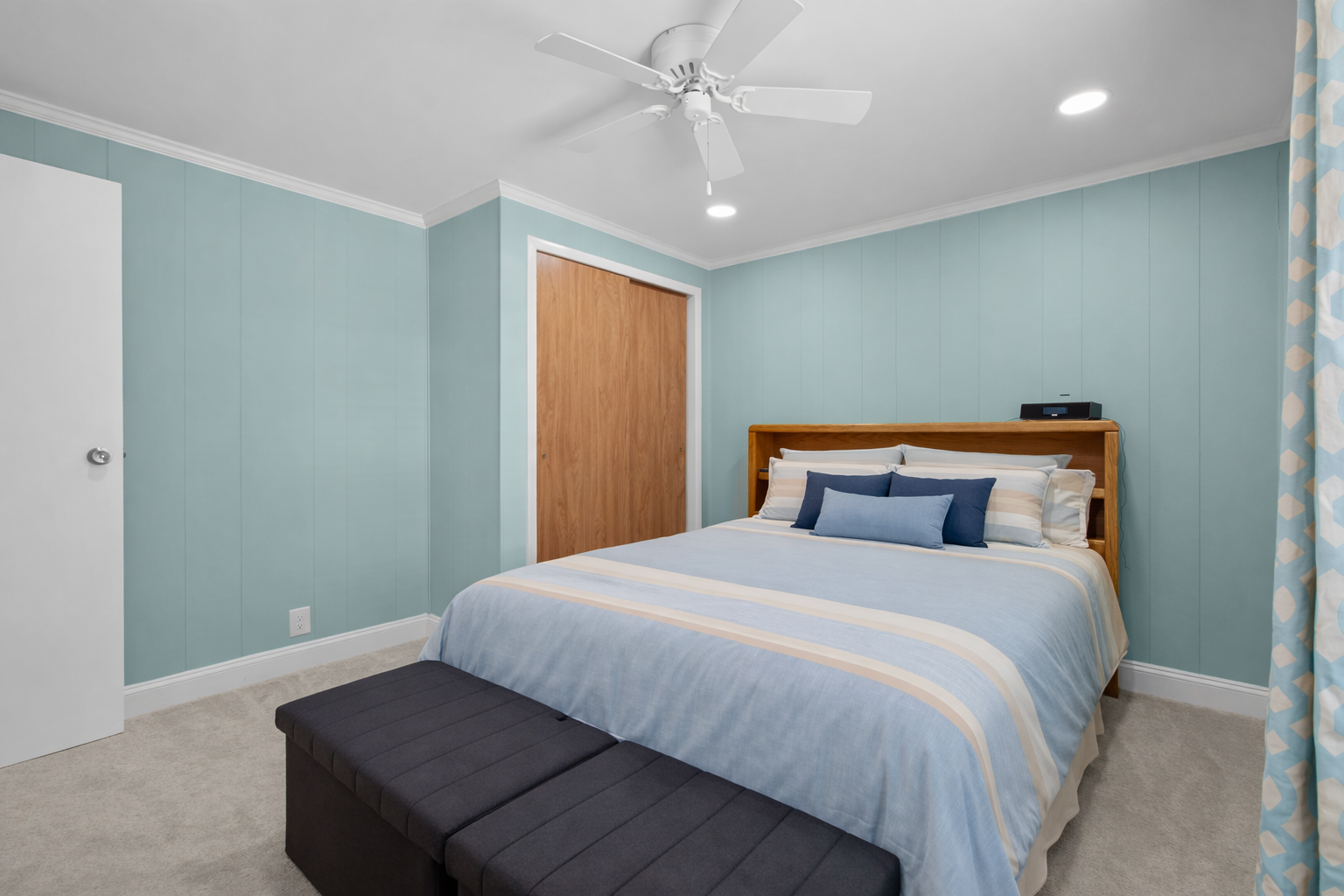 Drift off to sleep in your peaceful bedroom with calming seafoam walls, crisp linens, and a ceiling fan for cool comfort.