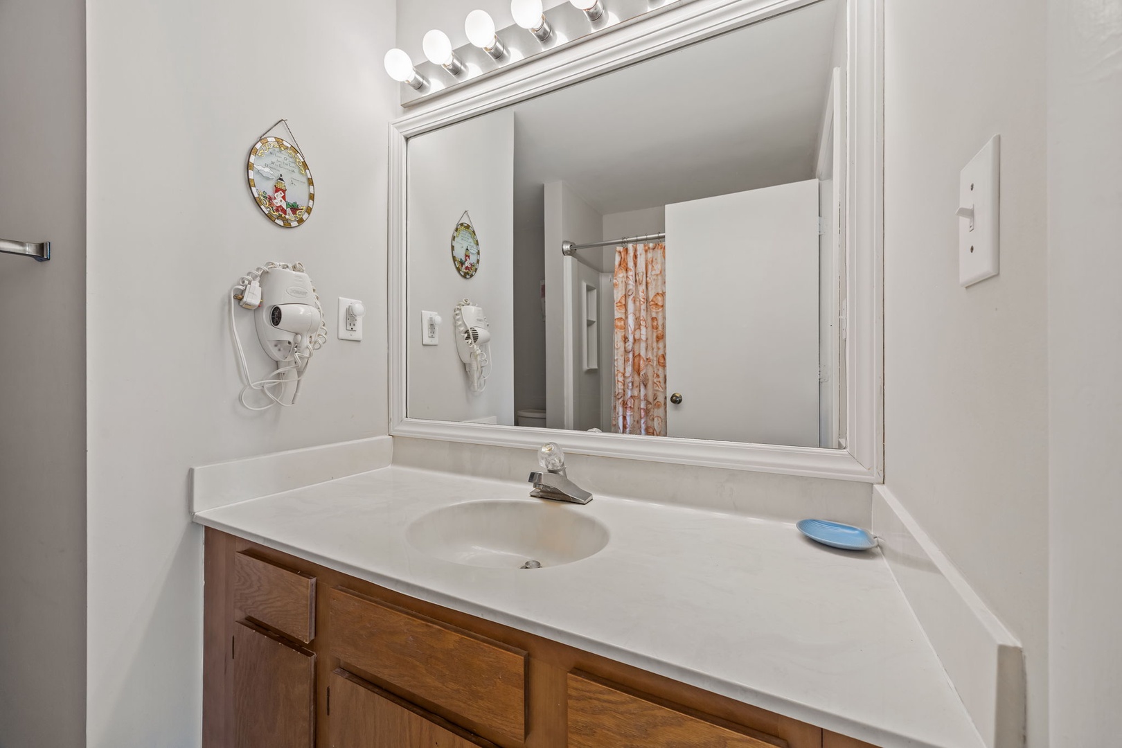Your private bathroom features bright vanity lighting and convenient amenities including a hair dryer for your comfort.