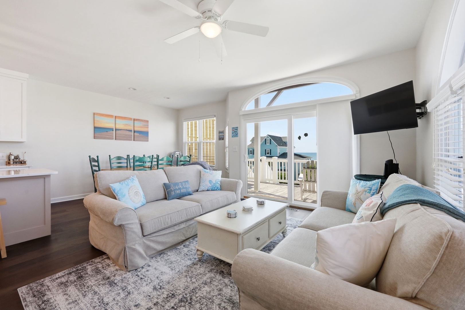 Relax in this bright coastal living space with soft seating, coastal accents, and a ceiling fan. Glass doors open to your private balcony with outdoor views.