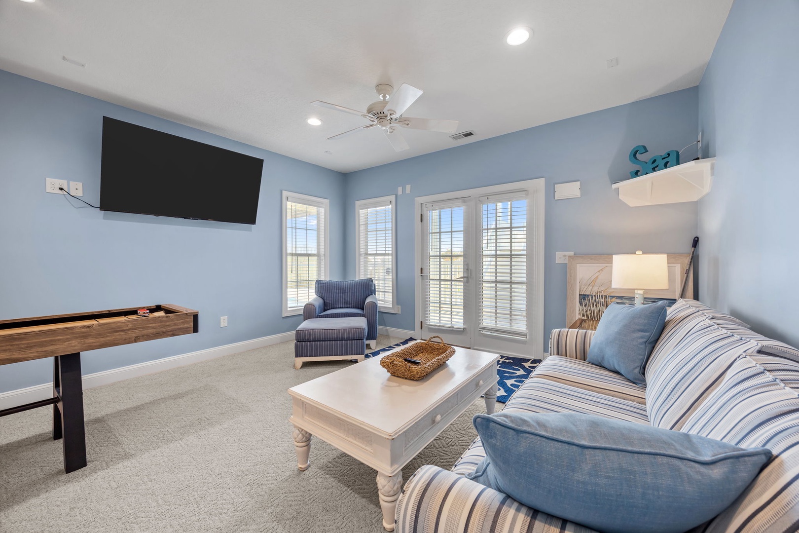 Relax in your serene blue living room with coastal charm, complete with comfortable seating, entertainment, and peaceful garden views.